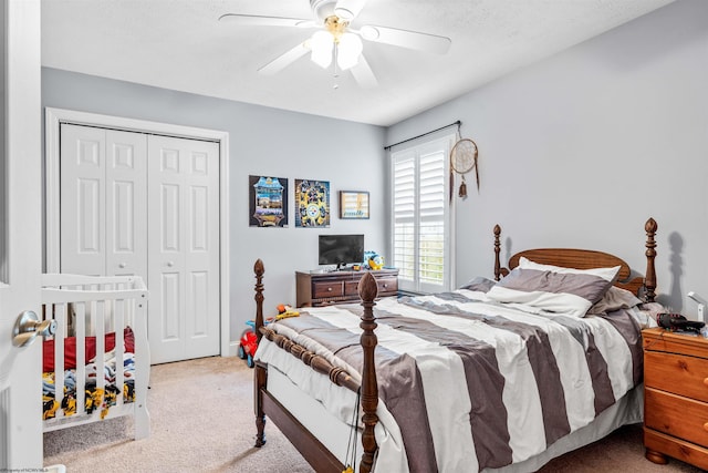 bedroom with ceiling fan, light colored carpet, a textured ceiling, and a closet