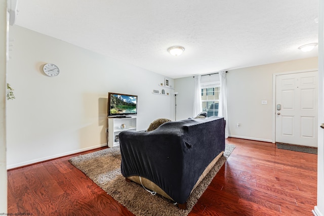 living room featuring a textured ceiling and dark hardwood / wood-style flooring