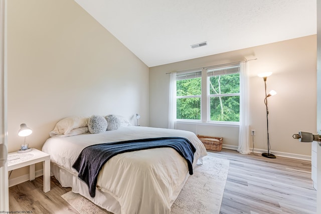 bedroom with light hardwood / wood-style flooring and vaulted ceiling