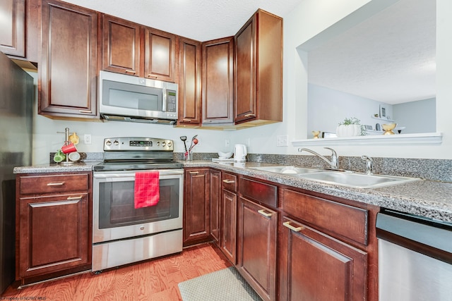 kitchen featuring light hardwood / wood-style flooring, stainless steel appliances, a textured ceiling, and sink