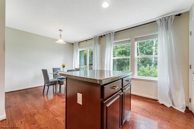 kitchen with pendant lighting, a textured ceiling, dark hardwood / wood-style floors, and a center island