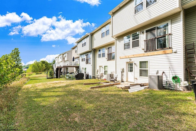 back of house featuring a lawn, a deck, and central AC