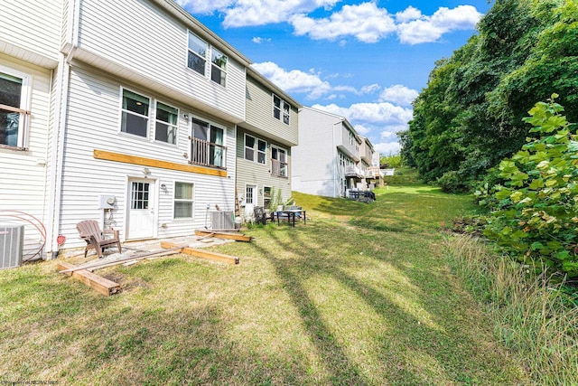 rear view of property with central AC unit and a yard