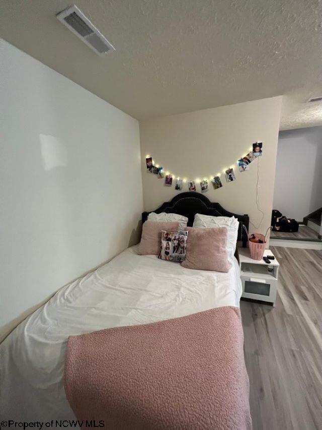 bedroom with a textured ceiling and hardwood / wood-style flooring