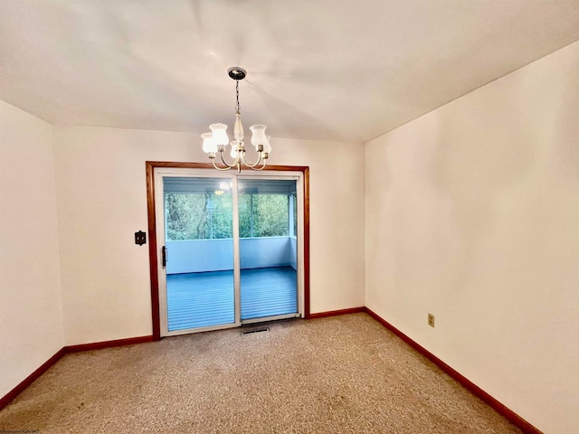 carpeted spare room with an inviting chandelier