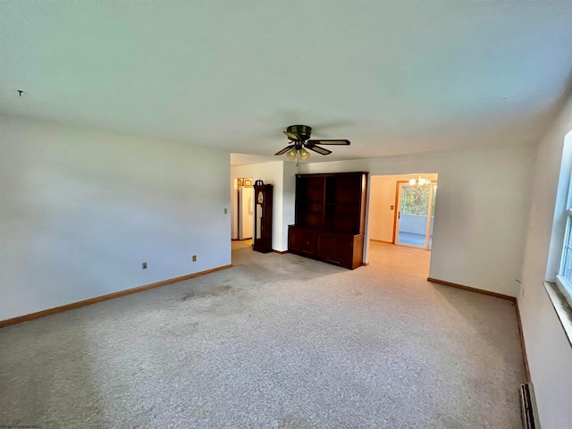 spare room featuring light colored carpet, a baseboard radiator, and ceiling fan with notable chandelier