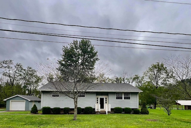 view of front of home featuring a front yard, an outbuilding, and a garage