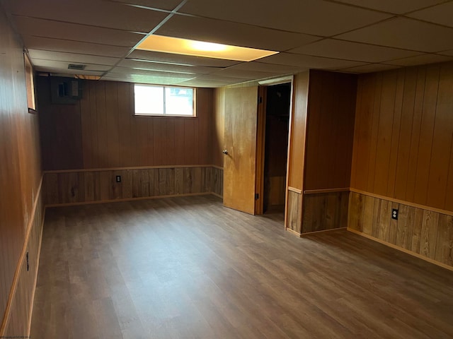 basement with a drop ceiling, wood walls, and dark hardwood / wood-style flooring