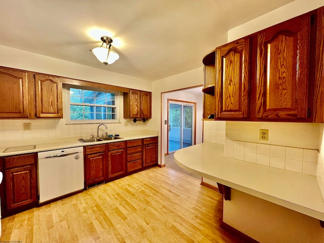 kitchen with light wood-type flooring, dishwasher, sink, and a wealth of natural light