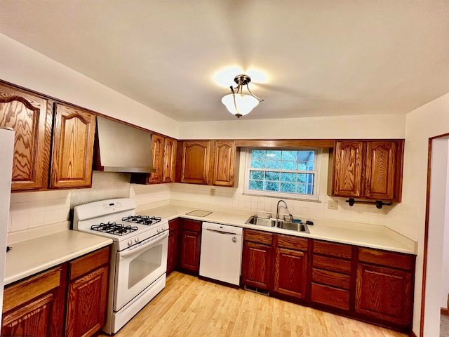 kitchen with sink, white appliances, light hardwood / wood-style flooring, backsplash, and wall chimney range hood