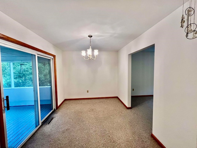 spare room featuring a chandelier and carpet