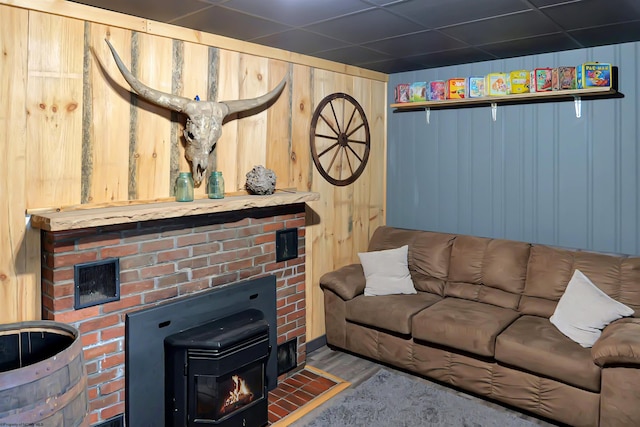 living room with hardwood / wood-style flooring, wooden walls, and a wood stove