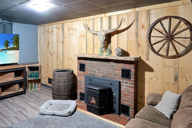 living room with wood walls, hardwood / wood-style floors, and a wood stove