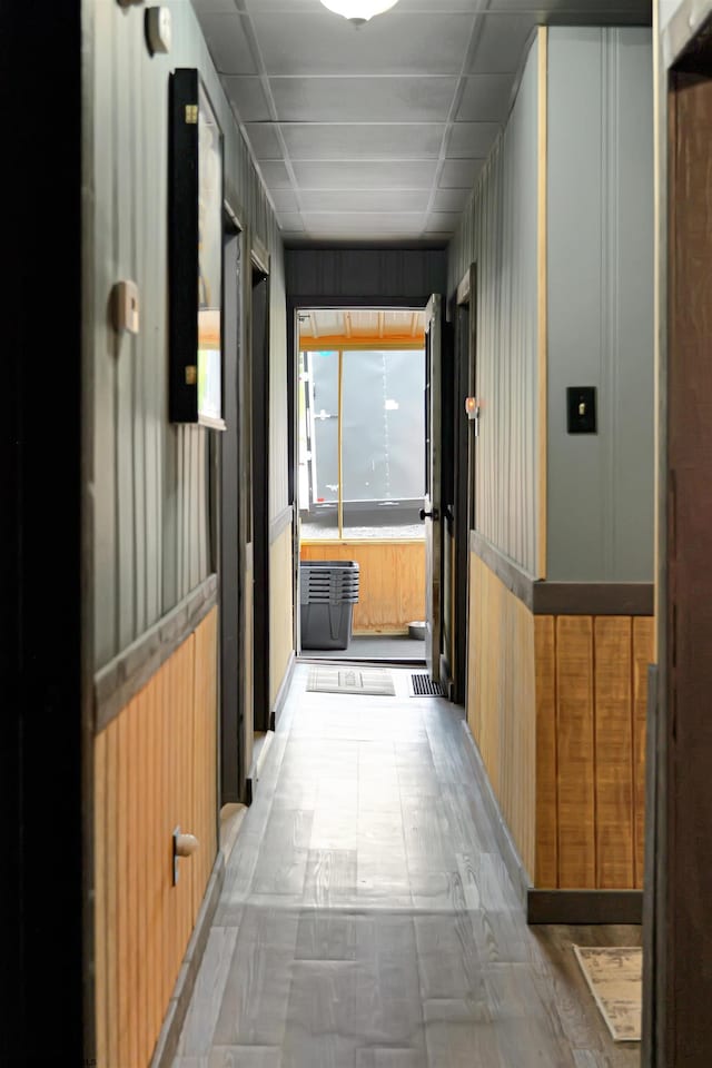 corridor with a paneled ceiling and wood walls