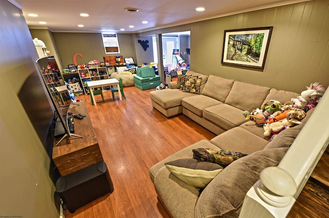 living room featuring wooden walls, wood-type flooring, and crown molding