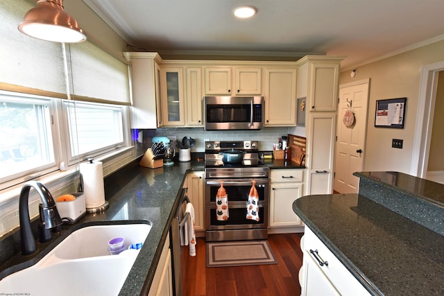 kitchen featuring pendant lighting, ornamental molding, sink, stainless steel appliances, and decorative backsplash