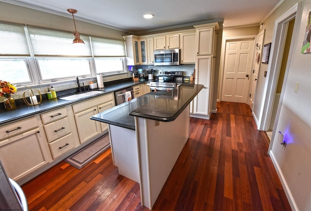 kitchen with a kitchen island, dark wood-type flooring, appliances with stainless steel finishes, crown molding, and decorative backsplash