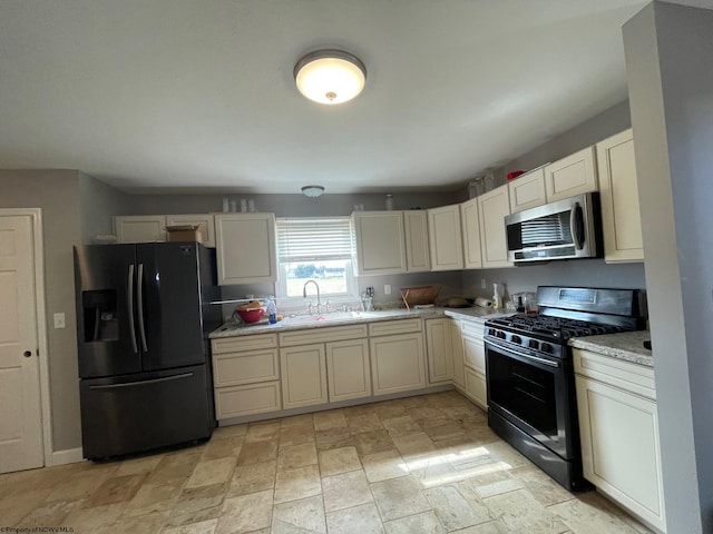 kitchen featuring black appliances, sink, and light stone counters