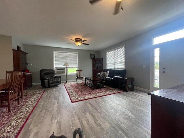 living room with ceiling fan, cooling unit, light hardwood / wood-style flooring, and a healthy amount of sunlight