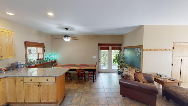 kitchen featuring light stone counters, kitchen peninsula, plenty of natural light, and ceiling fan