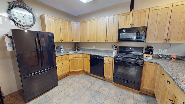 kitchen with black appliances, light brown cabinetry, sink, and light stone counters