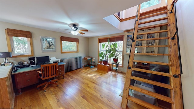 office area with ceiling fan, a skylight, light wood-type flooring, and a wealth of natural light