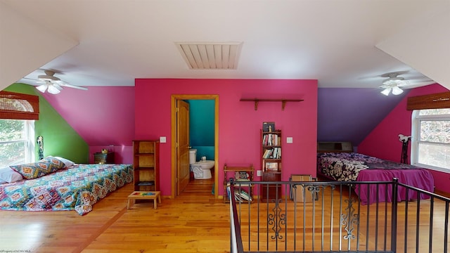 bedroom with ceiling fan, vaulted ceiling, hardwood / wood-style floors, and multiple windows