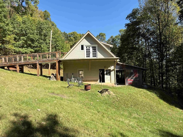 rear view of house featuring a wooden deck and a yard