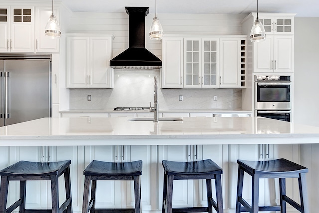 kitchen with white cabinets, custom exhaust hood, a large island, and a breakfast bar