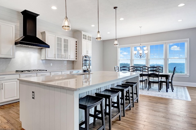 kitchen with a large island, white cabinetry, light hardwood / wood-style flooring, and custom range hood