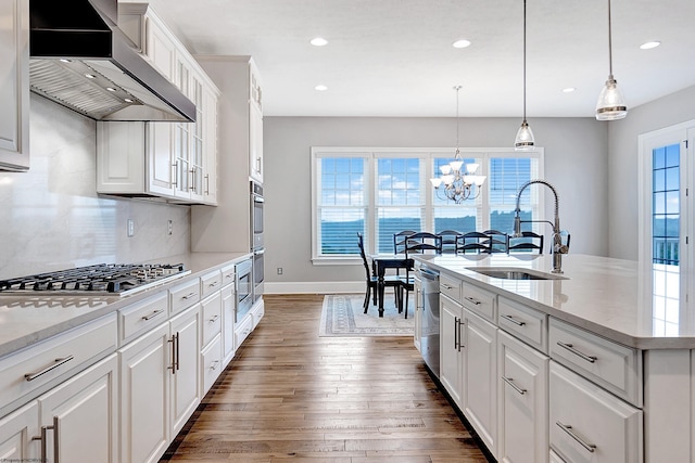 kitchen featuring a healthy amount of sunlight, white cabinetry, sink, and wall chimney range hood