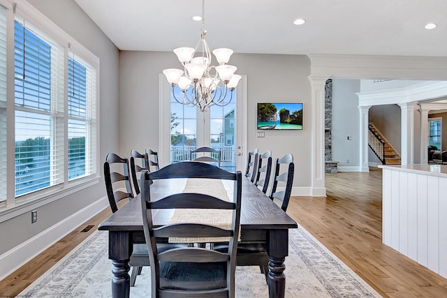 dining space with a wealth of natural light, a chandelier, light hardwood / wood-style floors, and ornate columns