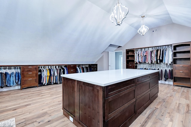 walk in closet featuring lofted ceiling, an inviting chandelier, and light hardwood / wood-style flooring