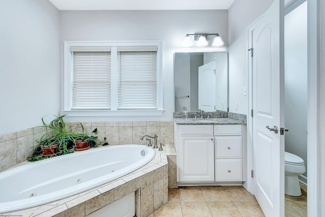 bathroom featuring tile patterned floors, tiled bath, vanity, and toilet