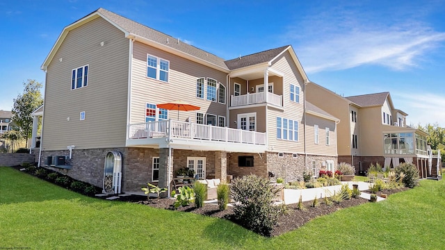 back of property featuring a balcony and a lawn