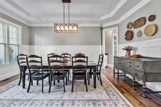 dining space with hardwood / wood-style flooring, a tray ceiling, and crown molding