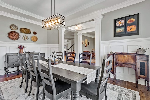 dining area with crown molding, decorative columns, and hardwood / wood-style flooring