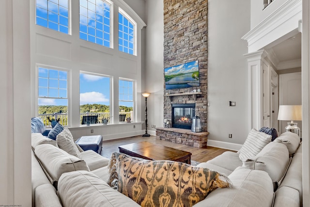 living room with crown molding, a high ceiling, a fireplace, and hardwood / wood-style floors