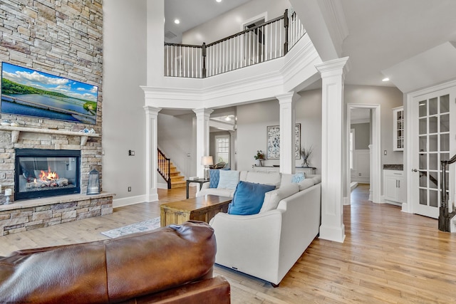 living room featuring a towering ceiling, light wood-type flooring, and a fireplace