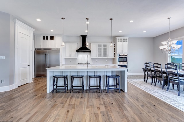 kitchen with custom range hood, light hardwood / wood-style floors, a kitchen breakfast bar, and appliances with stainless steel finishes