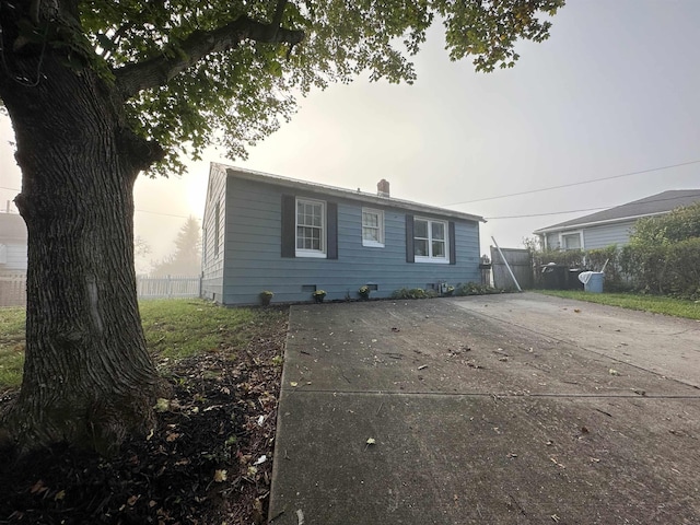 view of front facade with driveway, a chimney, fence, and a patio area