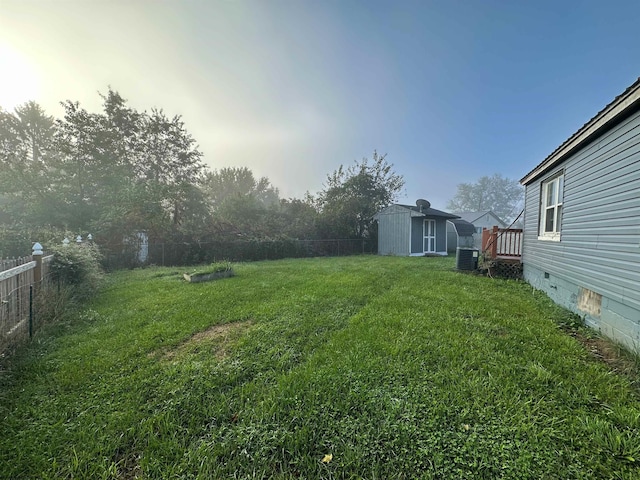 view of yard featuring central air condition unit, an outbuilding, a storage unit, and a fenced backyard