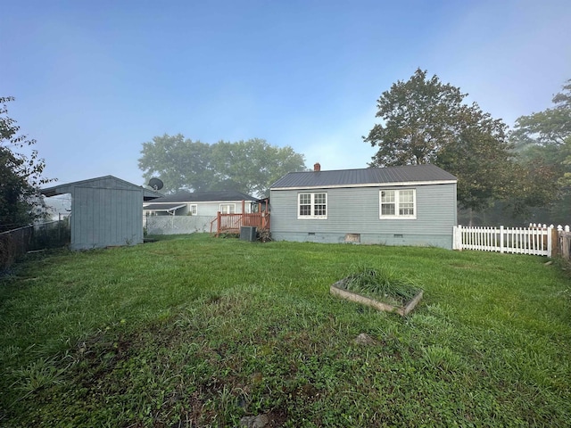 back of property with metal roof, a fenced backyard, crawl space, and a yard