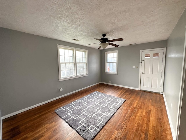 foyer entrance featuring baseboards, a textured ceiling, ceiling fan, visible vents, and wood finished floors