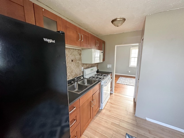 kitchen featuring backsplash, white appliances, a textured ceiling, light hardwood / wood-style flooring, and sink