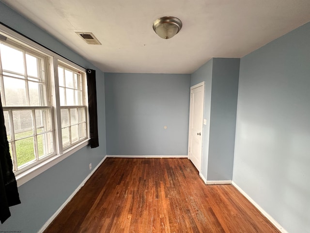 spare room featuring baseboards, visible vents, and wood finished floors