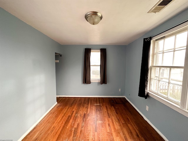 spare room with baseboards, visible vents, and wood finished floors