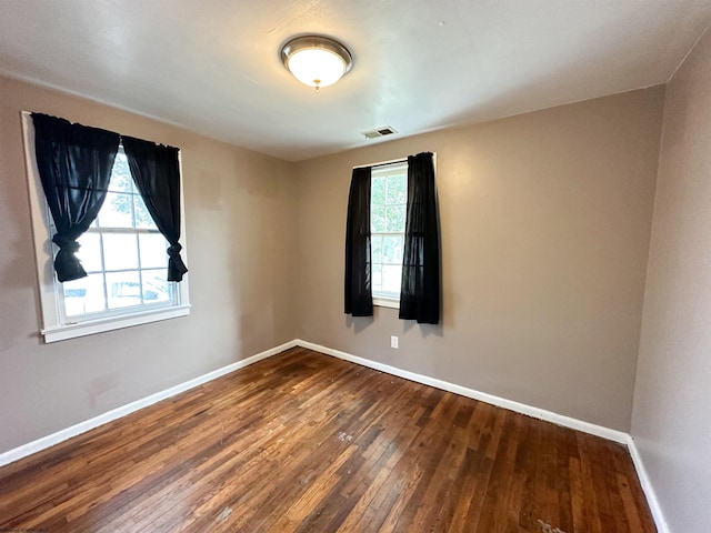 unfurnished room featuring baseboards, visible vents, and hardwood / wood-style floors