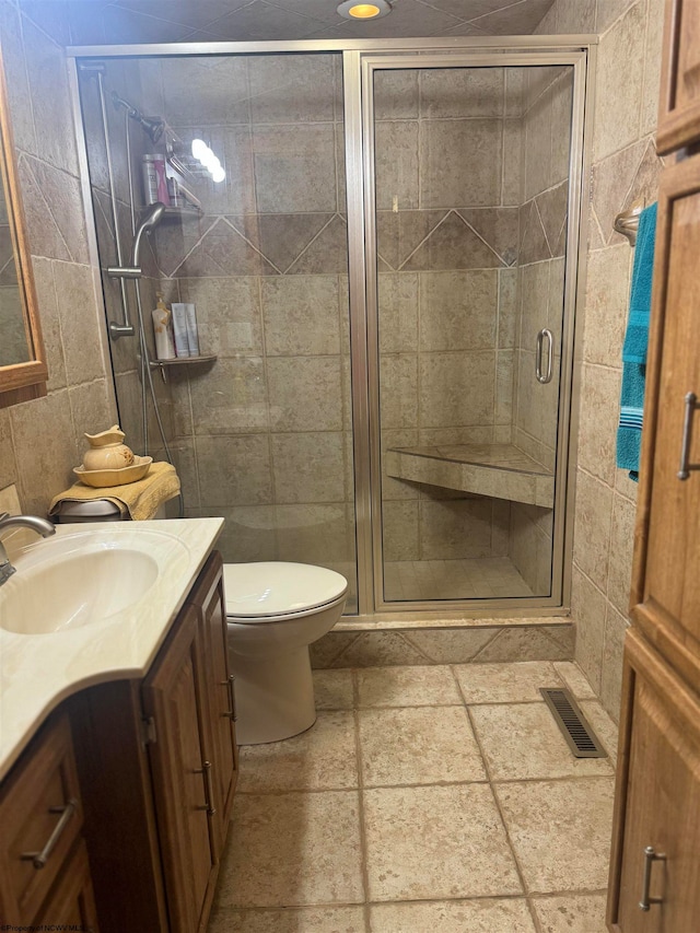 bathroom featuring tile walls, walk in shower, vanity, and toilet