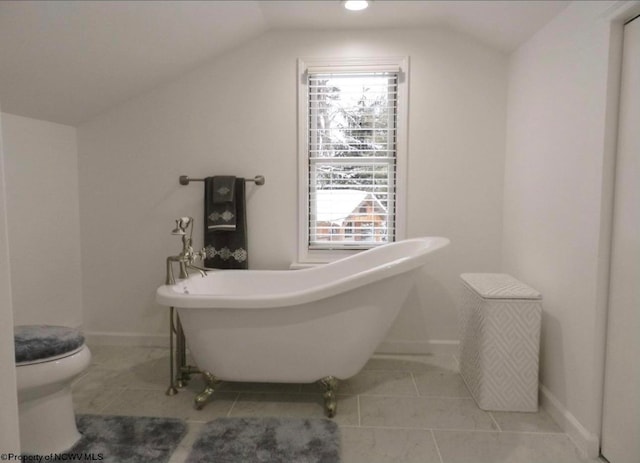 bathroom featuring lofted ceiling, tile patterned flooring, toilet, and a tub to relax in